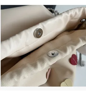 Detailed macro view of magnetic snap closures and heart-patterned lining of the beige bag