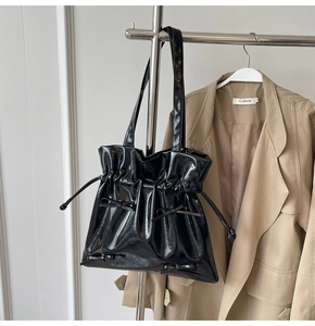 Detail of glossy black ballet-style tote bag with drawstring and cute bow accents