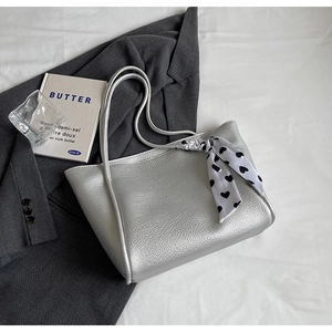 Detail of silver metallic tote bag featuring a heart-patterned silk scarf on the handle