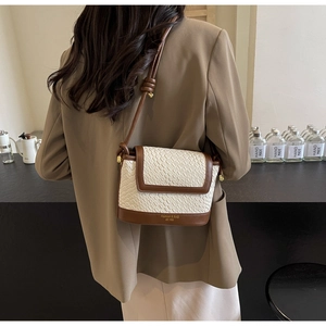 Détail du sac bandoulière tissé en paille avec bordure en cuir marron et sangle réglable