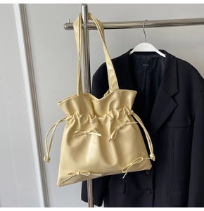 Close-up of cream pleated tote bag with bow details and drawstring closure for office wear