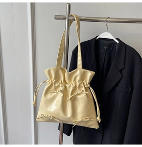 Detail of cream yellow ballet-style tote bag with drawstring folds and ribbon bows