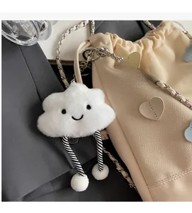 Detail of cute white cloud plush pendant and heart patch on beige canvas bucket bag