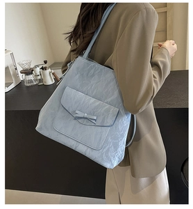 Détail du sac cabas bleu clair en tissu plissé avec un nœud sur la poche avant