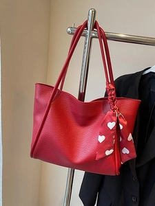 Large red pebbled leather tote bag with heart print scarf on silver display stand
