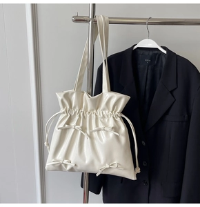 Close-up of cream white drawstring tote bag with elegant bow details and glossy finish