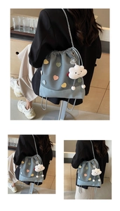 Detail view of light blue bucket bag with heart decor and cloud plush charm