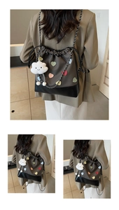Detail of dark brown bucket backpack featuring colorful heart patches and plush cloud charm