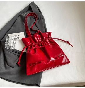 Close-up of bright red glossy tote bag with decorative bows and drawstring closure