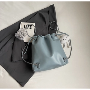 Detail of light blue bucket backpack with drawstring closure and silver chain strap
