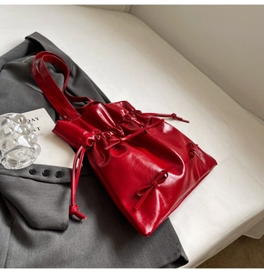 Detailed close-up of shiny red faux leather texture and small bow on the tote bag