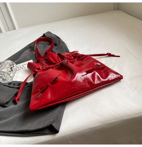 Detail of red ballet-style tote bag with bow decoration and glossy pleated texture