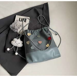 Macro view of blue canvas bucket bag with heart patches and cloud charm on a suit