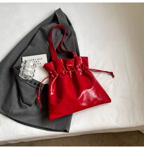 Detail view of the red glossy drawstring bucket bag featuring a chic pleated cloud design