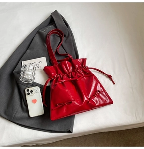 Detail of red patent leather tote bag with ballet style ribbons and drawstring closure
