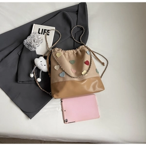 Detailed top view of a canvas bucket bag with heart patches and cloud charm on a table