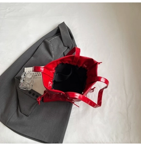 Close-up of bright red patent leather tote bag with pleated texture and drawstring detail