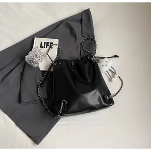 Detail of black leather drawstring bucket bag with silver chain and plush charm