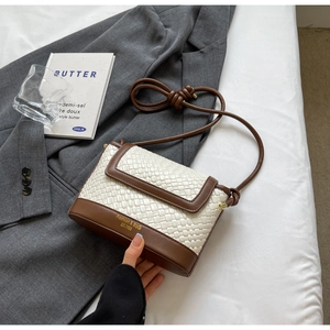 Détail de la texture cuir blanc tressé avec bordure marron sur ce sac bandoulière tendance