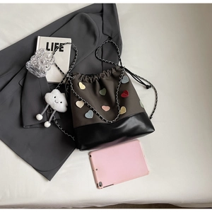 Top view of bucket bag featuring heart patches and plush charm with lifestyle props