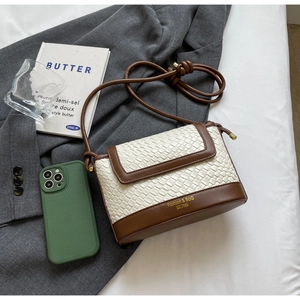 Détail du sac bandoulière en cuir tressé blanc avec bordure marron et logo doré