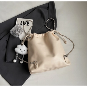 Detail view of cream drawstring bucket bag with chain strap and plush cloud charm