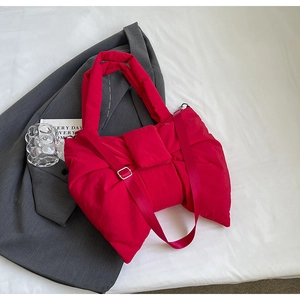Détail d'un sac nœud rouge rembourré avec bandoulière sur une veste grise chic