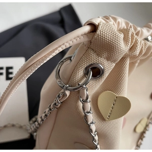 Close-up of canvas bucket bag featuring a yellow leather heart patch and drawstring detail