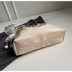 Detail view of the beige bucket bag with silver chain strap and cloud charm ornament