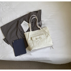 Sac cabas crème à nœud papillon avec texture plissée brillante en vue à plat chic
