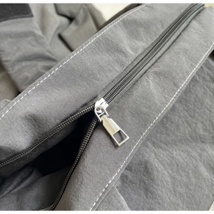 Gros plan détaillé sur la fermeture éclair et les coutures d'un sac cabas gris style ballet