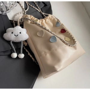 Detail of beige bucket bag with colorful heart patches, chain strap, and cloud charm