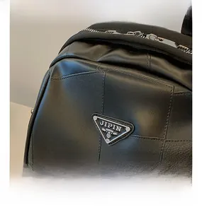 Close-up of black leather texture with triangular metal logo and silver zipper detail