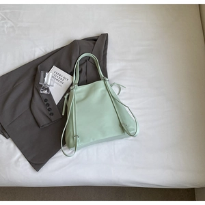 Détail d'un sac cabas vert menthe avec cordons de serrage sur un fond esthétique épuré