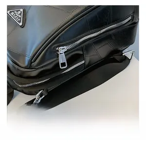 Macro shot of silver metal zipper and brand logo on a black quilted leather backpack