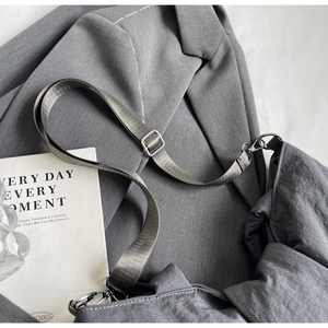 Vue détaillée du sac bandoulière en nylon gris avec sangle ajustable et boucles métal