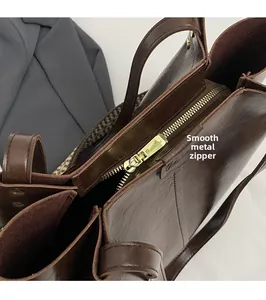 Dettaglio macro della cerniera in metallo dorato sulla borsa tote in pelle marrone scuro