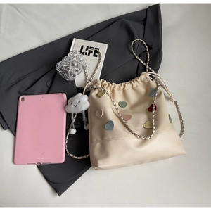 Detail of beige bucket bag with colorful heart patches and cloud plush charm detail