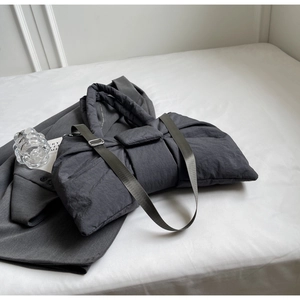 Détail d'un sac à bandoulière matelassé gris foncé avec poignées et sangle large