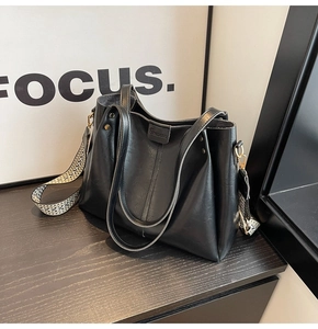 Dettaglio della borsa tote in pelle nera con tracolla larga in tessuto etnico