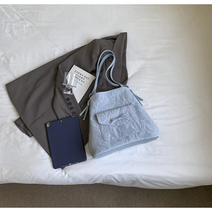 Gros plan du sac fourre-tout bleu clair avec texture plissée et poche à nœud papillon