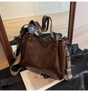 Dettaglio borsa tote in pelle marrone con ampia tracolla a motivi geometrici colorati