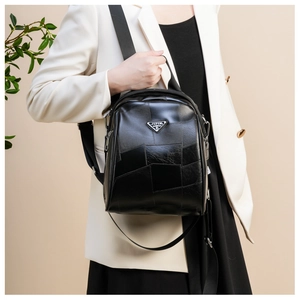 Detail view of the black leather backpack with geometric texture and metal logo