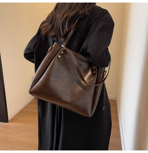 Vista dettagliata della grande borsa tote in pelle marrone scuro con rivetti e tracolla