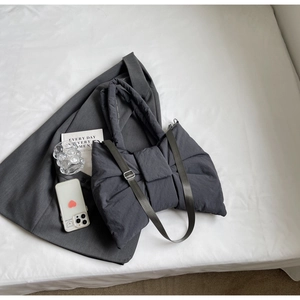 Détail du sac cabas en nylon gris foncé avec nœud, texture matelassée et bandoulière