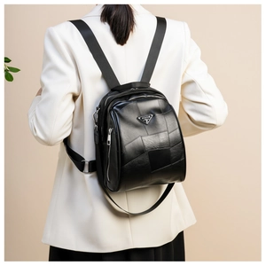 Close-up of black leather backpack featuring triangle metal logo and side zipper detail