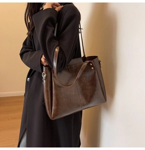 Dettaglio borsa tote marrone scuro con fibbia in metallo e logo in rilievo