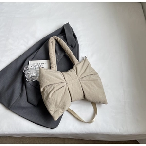 Vue de dessus d'un sac à main beige en nylon en forme de nœud avec texture rembourrée