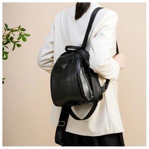 Detail view of the black leather backpack featuring patchwork design and metal logo