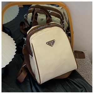 Macro view of textured cream PU leather backpack with brown trim and metal logo